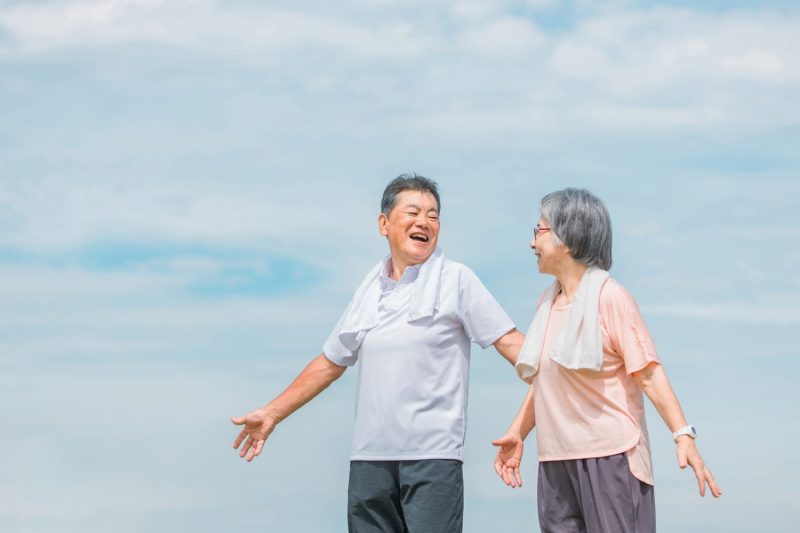 公園でストレッチ・深呼吸をする高齢者夫婦