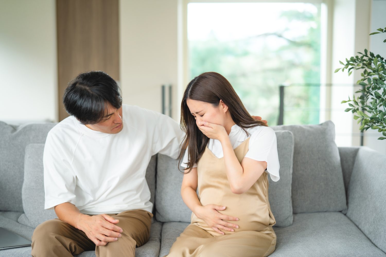 吐き気をもよおす妊婦と心配する男性