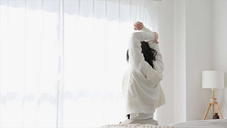 朝起きて伸びをする女性