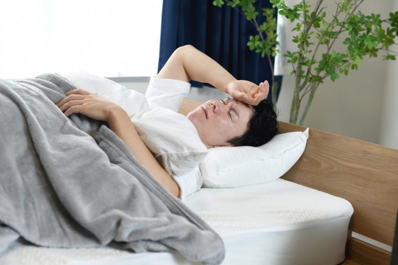 睡眠中に苦しそうな表情をする男性