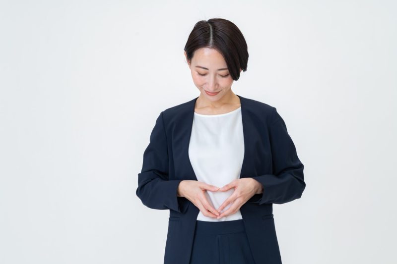 お腹にハートマークを作る女性