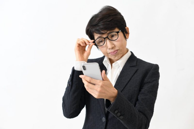 スマホを見る老眼に悩む中高年の女性