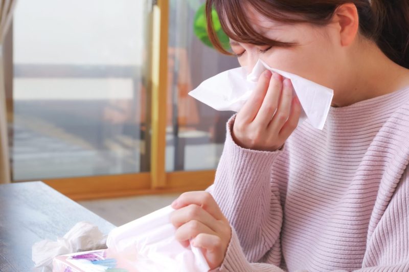 ティッシュで鼻をかむ女性