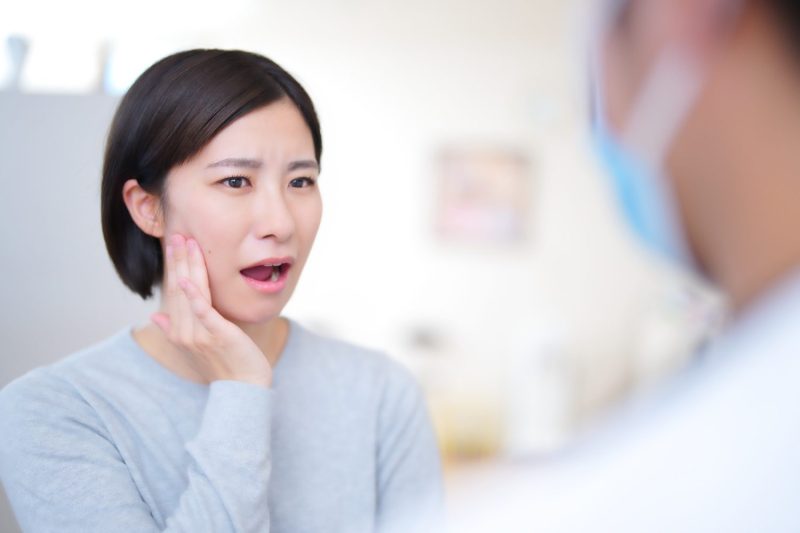 口を開けて頬を抑える女性患者と医者