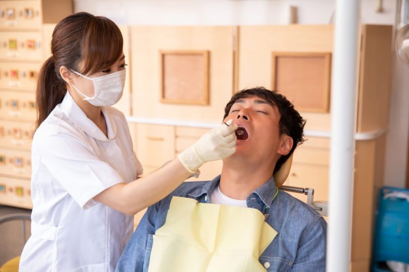 歯科衛生士に施術を受ける男性