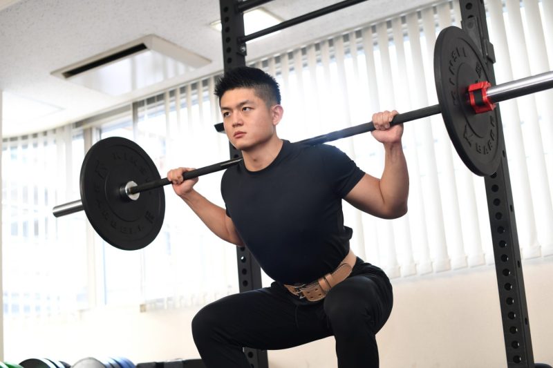 ジムでスクワットをする男性