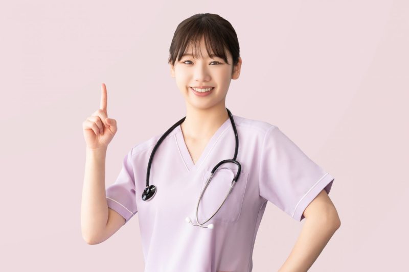 人差し指を立てて案内する女性医療スタッフ