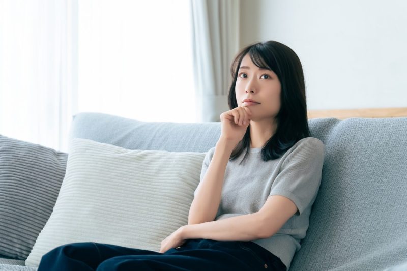 ソファに座って考えごとをする女性