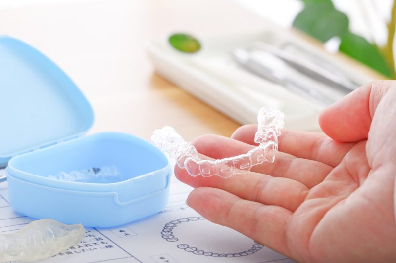 歯科医療で使用するマウスピースをもつ男性