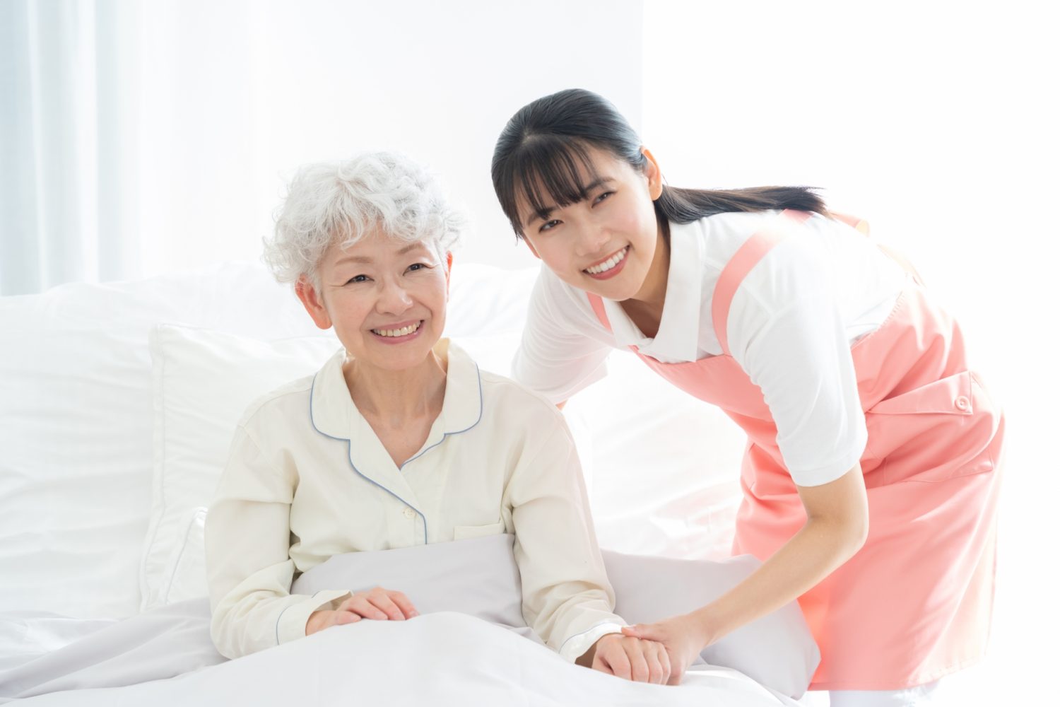 寝ているシニア女性を介護をする介護士