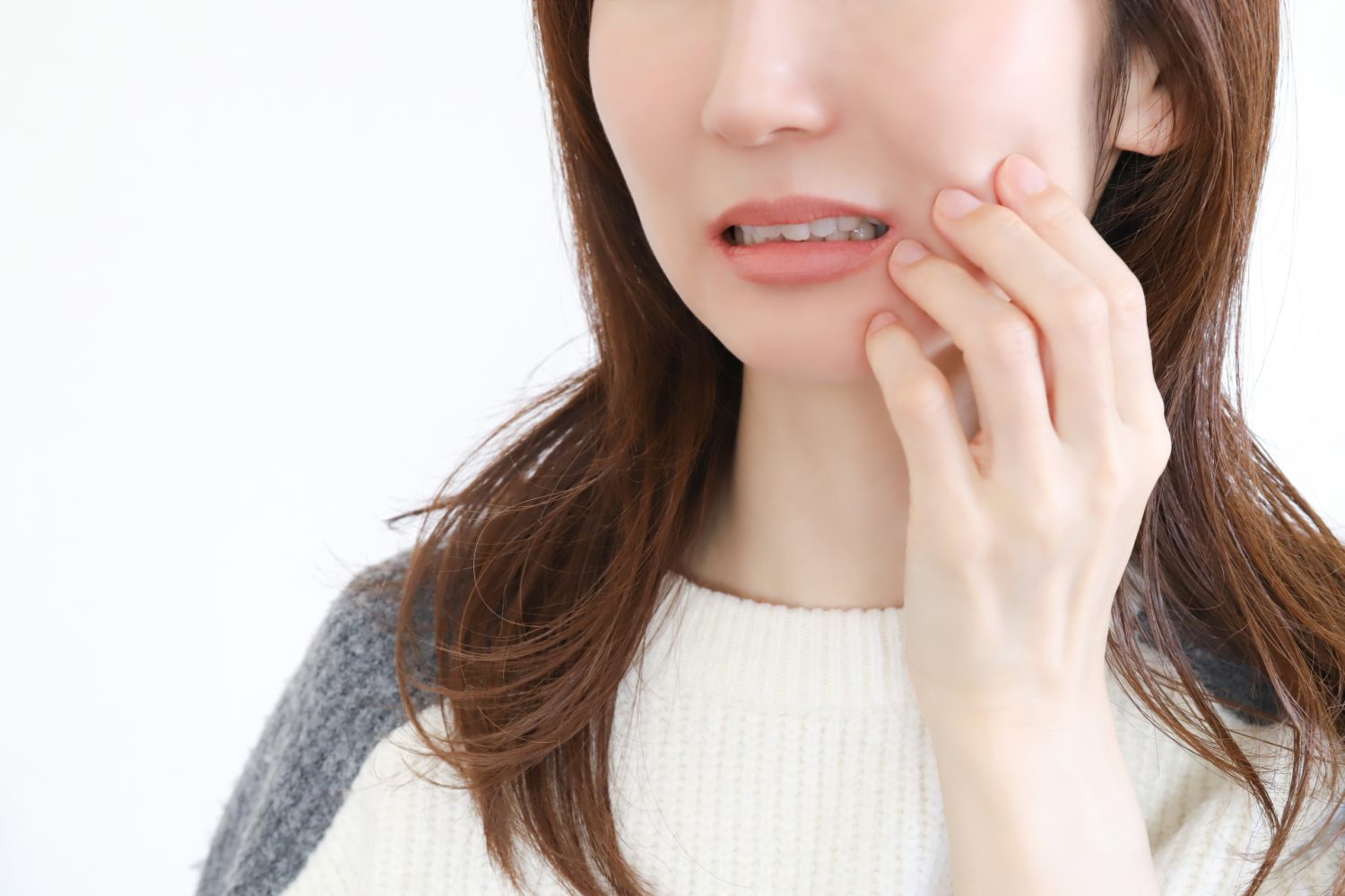 歯の痛み　ほっぺたを押さえる女性